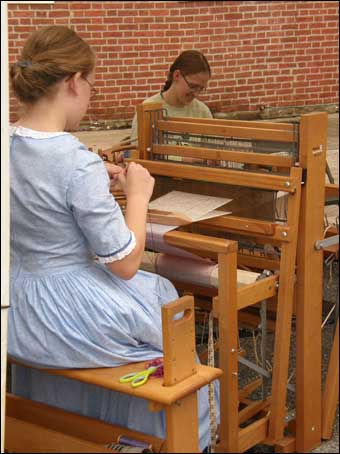 Reenactors weaving on a loom