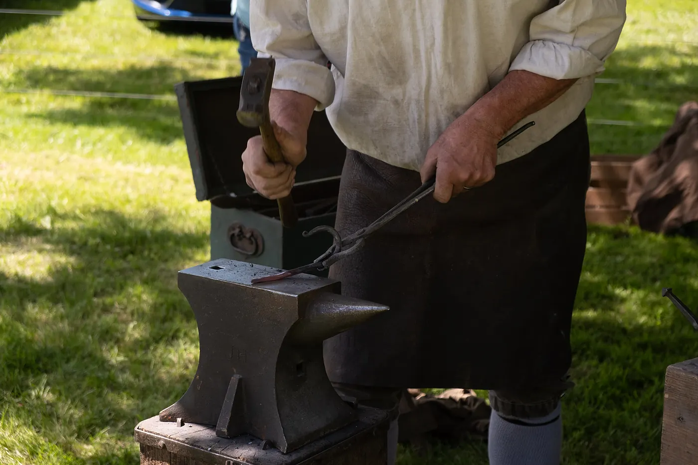 A blacksmith working iron with hammer and tongs at an anvil
