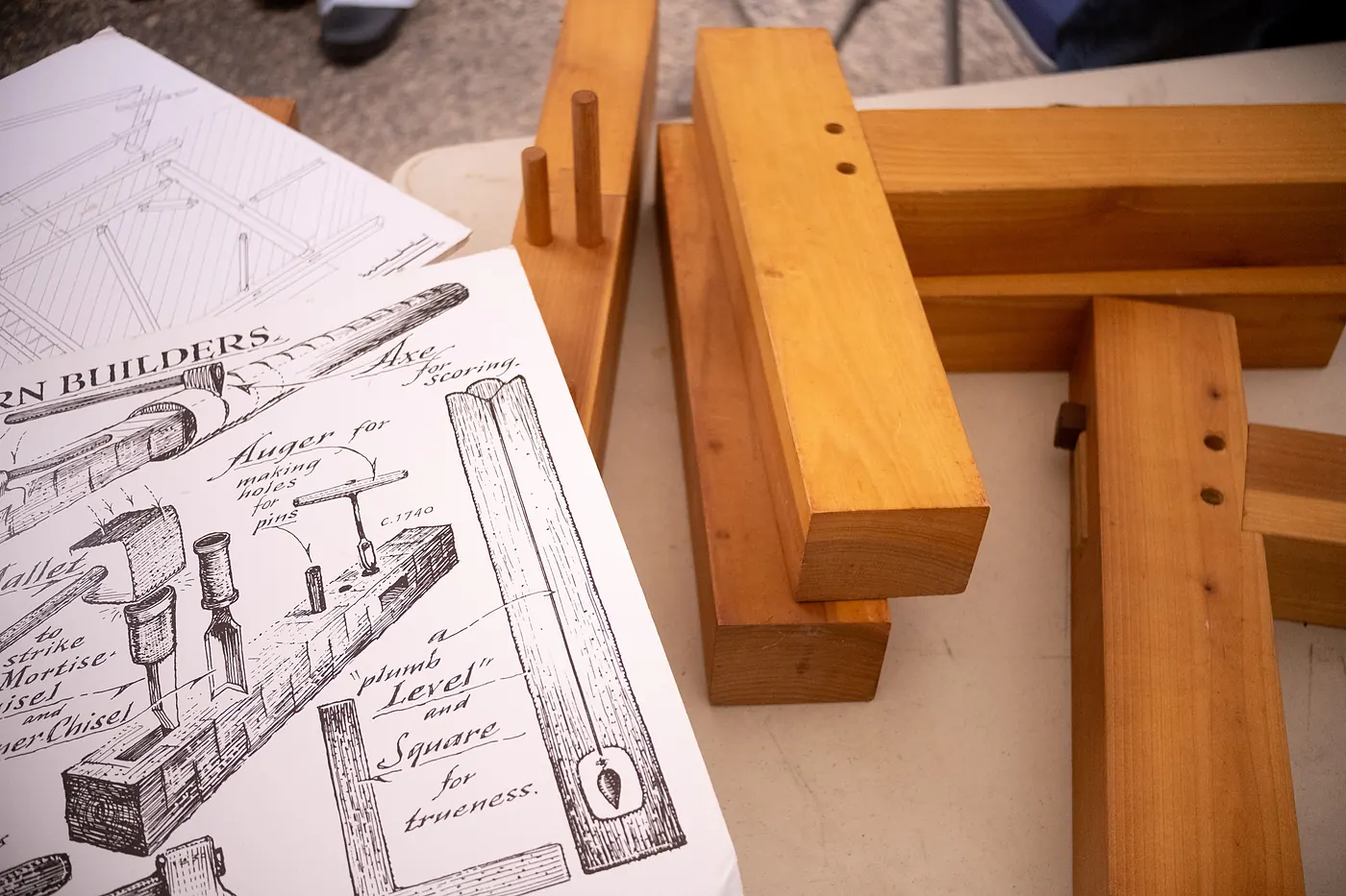 Pegged timber-frame joints beside an illustrated sheet of colonial barn builders' tools